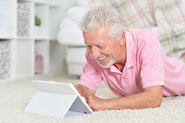 Portrait d'un bel homme âgé utilisant une tablette à la maison