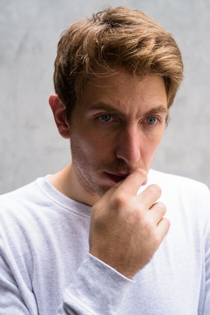 Portrait de bel homme aux cheveux blonds sur un mur de béton dans les rues à l'extérieur