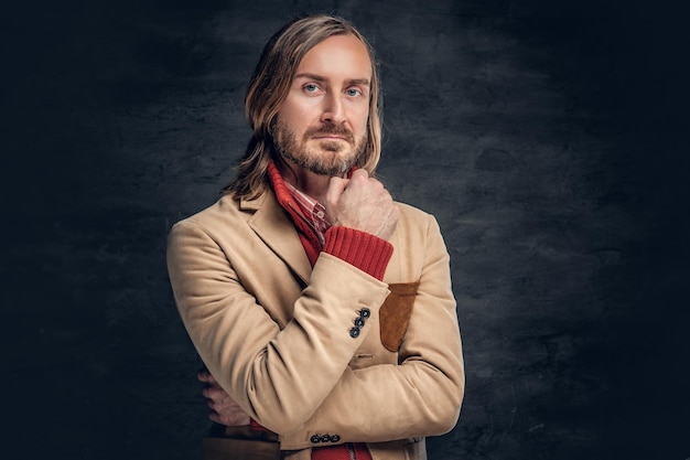 Portrait d'un bel homme barbu aux cheveux longs vêtu d'une veste jaune et d'une chemise rouge.