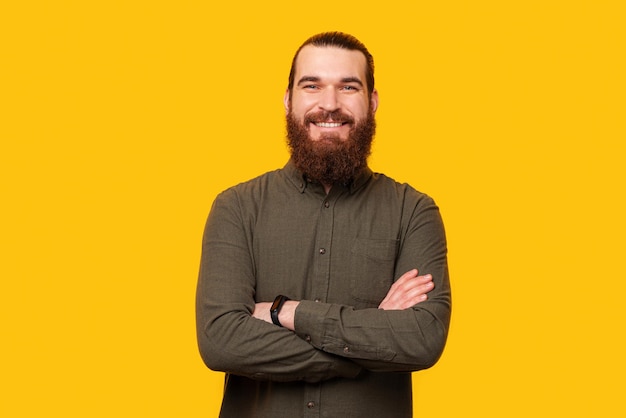 Portrait d'un bel homme barbu souriant puissant avec les bras croisés