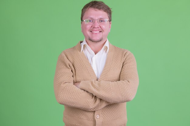 Portrait de bel homme barbu en surpoids avec des lunettes contre clé chroma ou mur vert