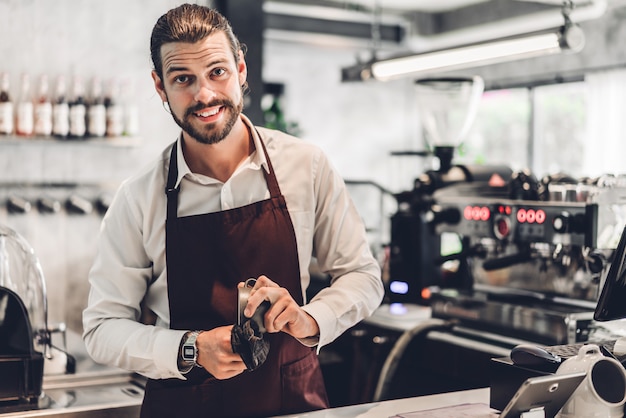 Portrait de bel homme barista barbu propriétaire de petite entreprise travaillant derrière le comptoir bar dans un café