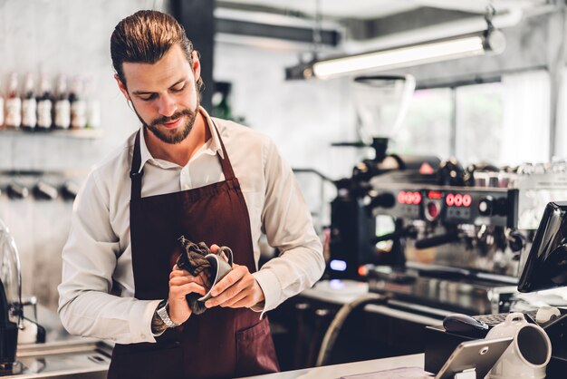 Portrait de bel homme barista barbu propriétaire de petite entreprise travaillant avec un ordinateur portable derrière le comptoir bar dans un café