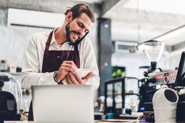 Portrait de bel homme barista barbu recevant la commande du client