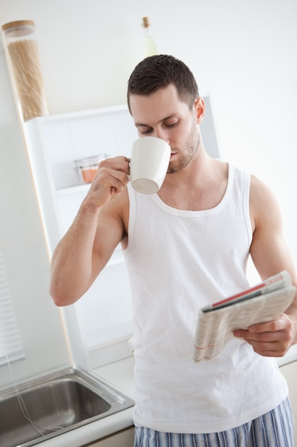 Portrait d&#39;un bel homme buvant du thé en lisant les nouvelles