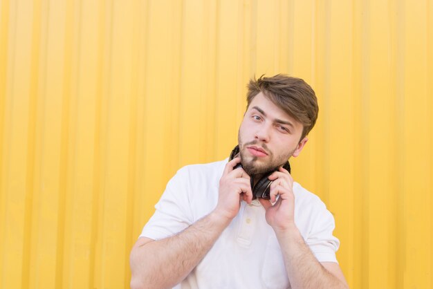 Portrait d'un bel homme avec un casque sur le cou contre un mur jaune