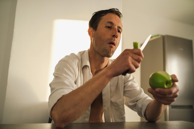 Portrait d'un bel homme coupant et mangeant une pomme