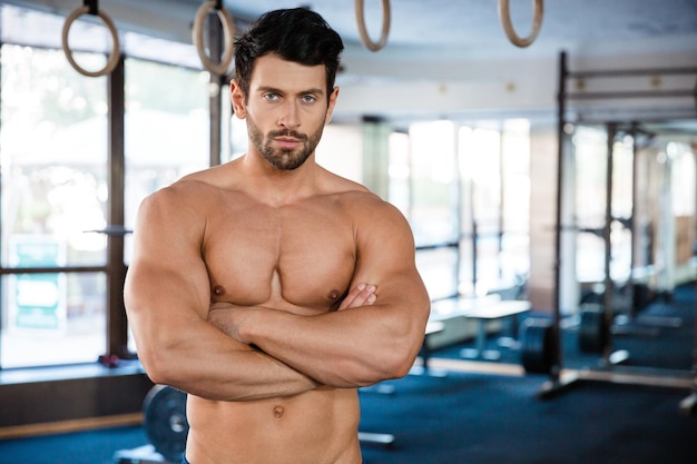 Portrait d'un bel homme debout avec les bras croisés dans la salle de fitness