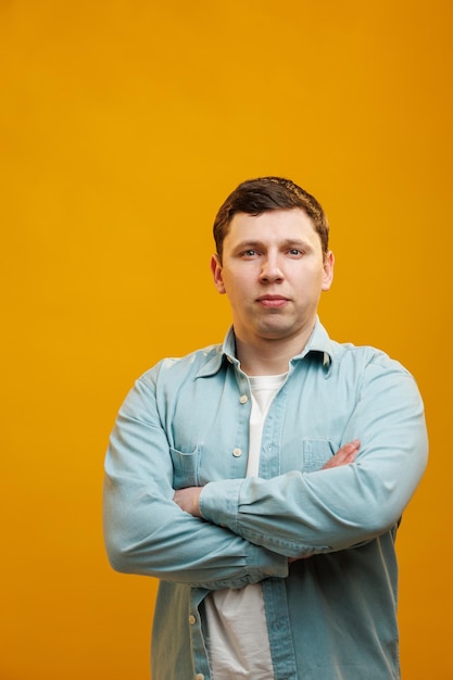 Portrait d'un bel homme européen en chemise regardant la caméra debout sur fond de studio jaune