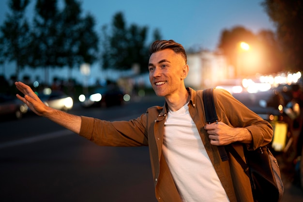 Photo portrait de bel homme hélant pour un taxi la nuit dans la ville