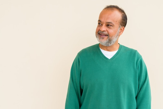 Portrait d'un bel homme indien avec une barbe grise contre un mur uni