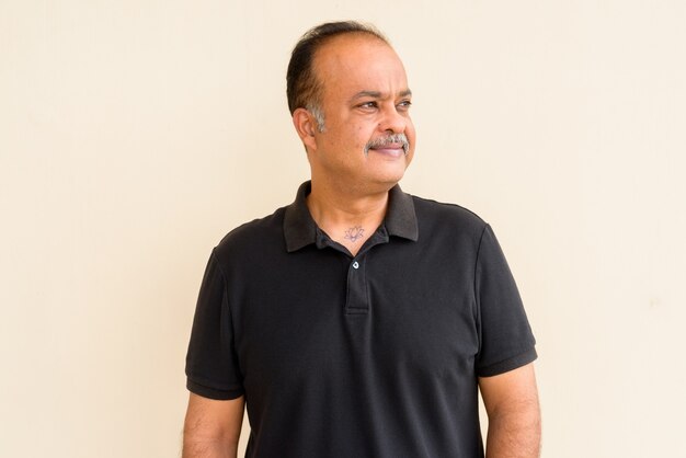 Portrait d'un bel homme indien avec une barbe grise contre un mur uni