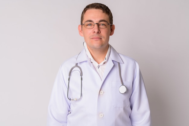 Portrait de bel homme médecin contre le mur blanc