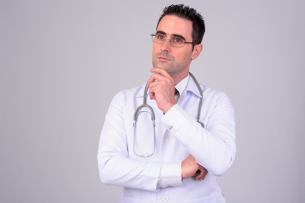 Portrait de bel homme médecin pensant sur blanc