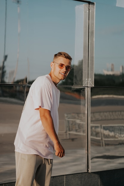 Portrait d'un bel homme en milieu urbain. Un jeune homme dans le contexte d'un bâtiment miroir en verre moderne