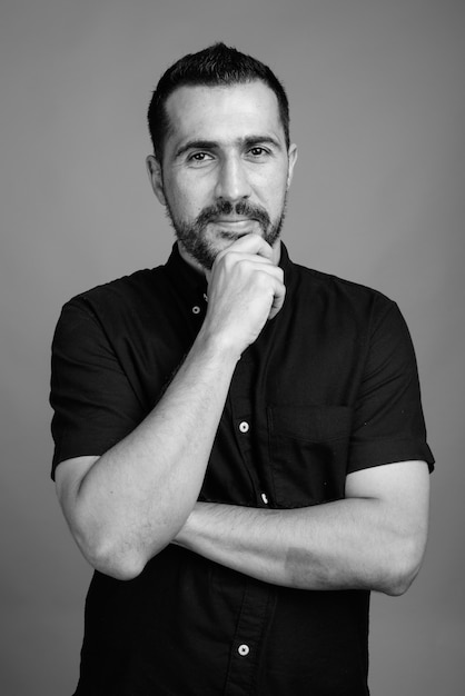 Portrait d'un bel homme persan barbu portant une chemise noire sur gris en noir et blanc