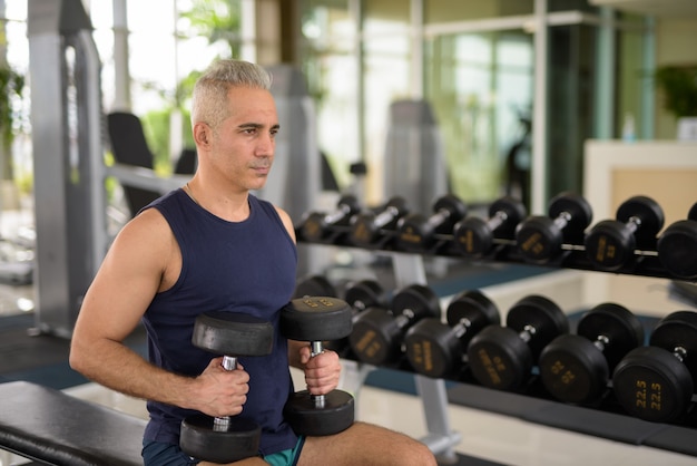 Portrait d'un bel homme persan mature aux cheveux gris faisant de l'exercice dans la salle de sport