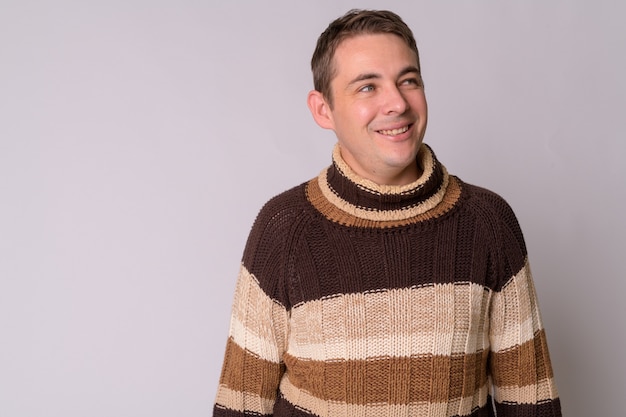 Portrait de bel homme portant un pull à col roulé contre le mur blanc