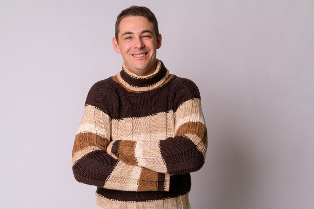 Portrait de bel homme portant un pull à col roulé contre le mur blanc