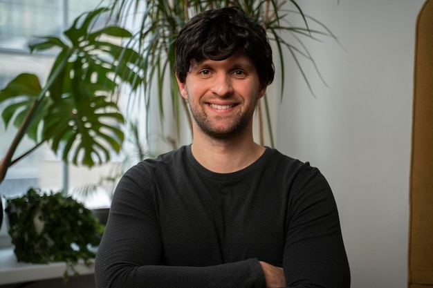 Portrait d'un bel homme regardant la caméra et souriant dans le salon d'un appartement moderne