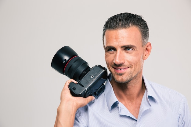 Portrait d'un bel homme souriant tenant la caméra et regardant loin isolé