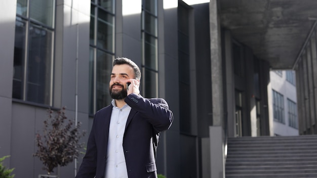 Portrait de bel homme souriant en tenue décontractée, parler sur le smartphone.