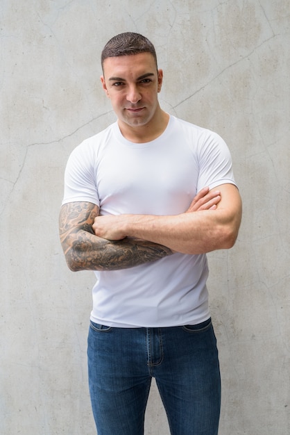 Portrait de bel homme avec des tatouages contre le mur de béton