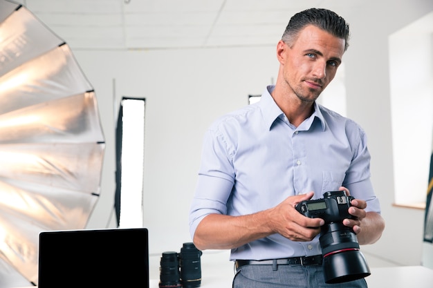 Portrait d'un bel homme tenant une caméra en studio