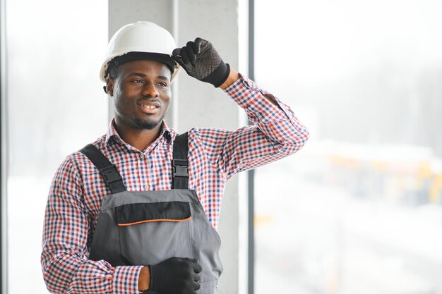 Photo portrait d'un bel ouvrier ou ingénieur africain en combinaison et en chapeau dur