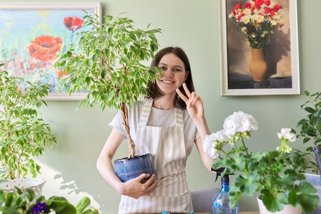 Portrait d'une belle adolescente souriante avec des plantes en pot. Culture et entretien des plantes d'intérieur. Passe-temps et loisirs, jardinage domestique, jungle urbaine, concept d'amis en pot