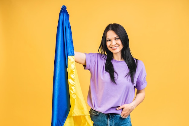 Portrait de belle belle belle femme gaie heureuse tenant dans les mains le drapeau ukrainien s'amusant isolé sur fond de couleur pastel jaune