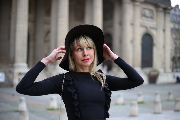 Portrait d'une belle blonde dans une robe noire et un chapeau noir