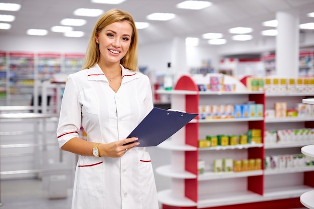 Portrait de belle blonde pharmacien femme agréable écrit sur le presse-papiers