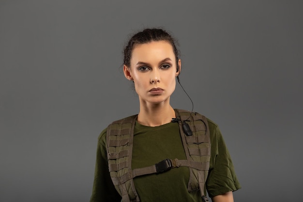 Portrait d'une belle brune bouclée avec une expression sérieuse sur le visage d'une femme soldat