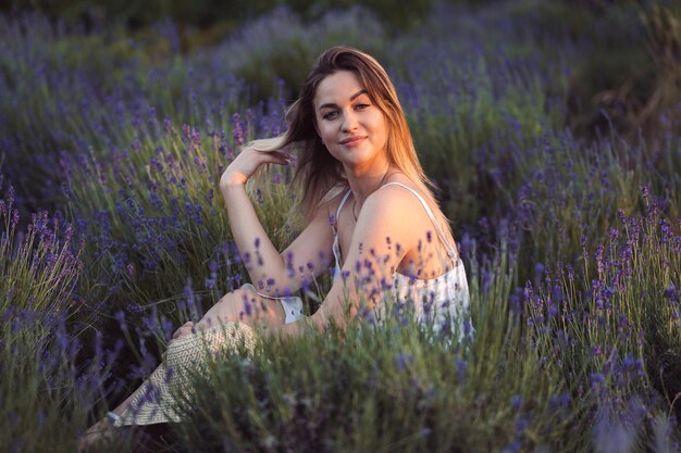 Portrait d'une belle brune dans un champ de lavande fille redresse ses cheveux avec plaisir