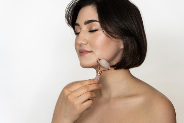 Portrait d'une belle brune une peau lisse à l'aide d'un rouleau derma pour son visage