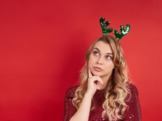 Portrait de belle dame rêveuse avec bandeau de Noël isolé sur fond rouge