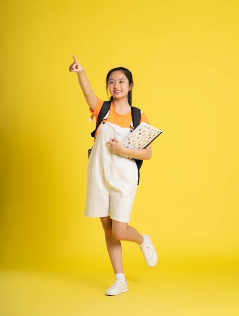 portrait d'une belle écolière asiatique portant un sac à dos sur fond jaunexA