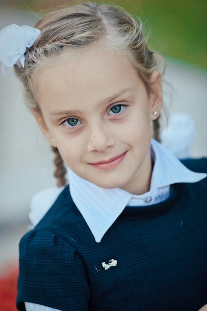 Portrait d'une belle écolière avec une queue de cochon et un arc blanc