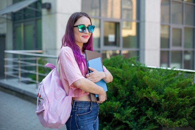 Portrait belle écrivaine vêtue d'une tenue décontractée tenant un ordinateur portable moderne à la main avec un sac à dos.