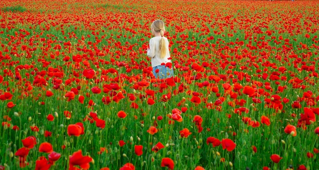 Portrait de la belle enfant fille porte des vêtements décontractés dans le champ de fleurs de pavot Famille sur le champ de pavot de printemps