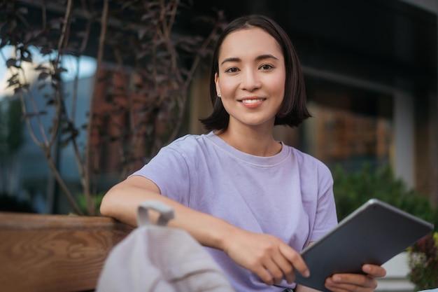 Portrait d'une belle étudiante asiatique souriante étudiant à l'aide d'une tablette numérique, concept d'éducation en ligne