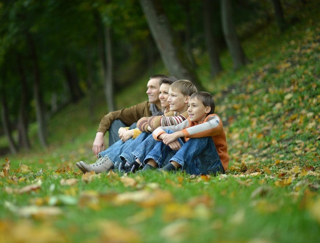 Portrait d'une belle famille heureuse s'asseyant dans le parc d'automne