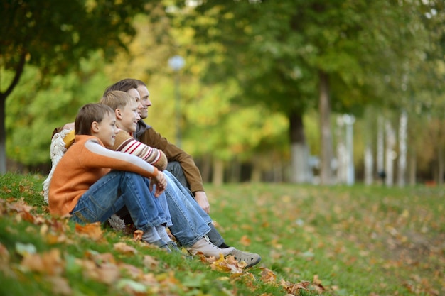 Portrait d'une belle famille heureuse s'asseyant dans le parc d'automne