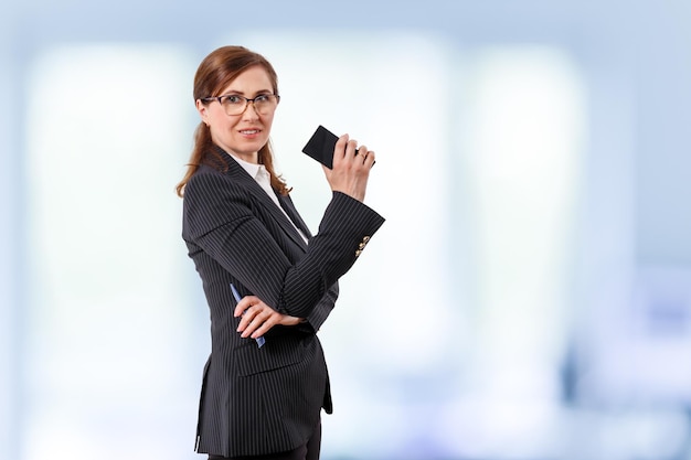 Portrait d'une belle femme d'affaires de 50 ans avec un téléphone portable au bureau