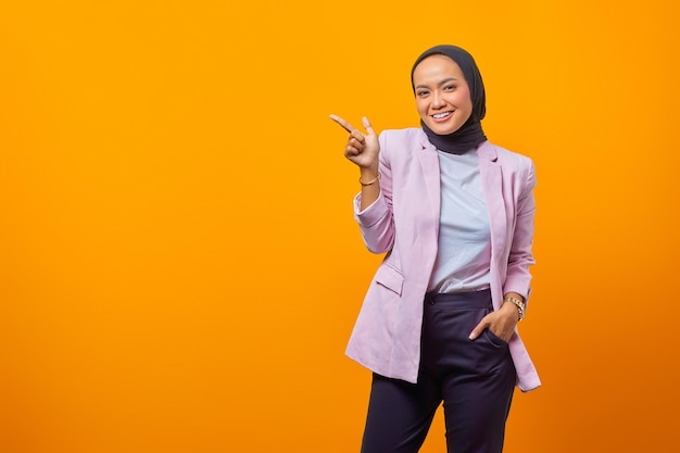 Portrait de belle femme d'affaires asiatique pointant et regardant la caméra sur fond jaune