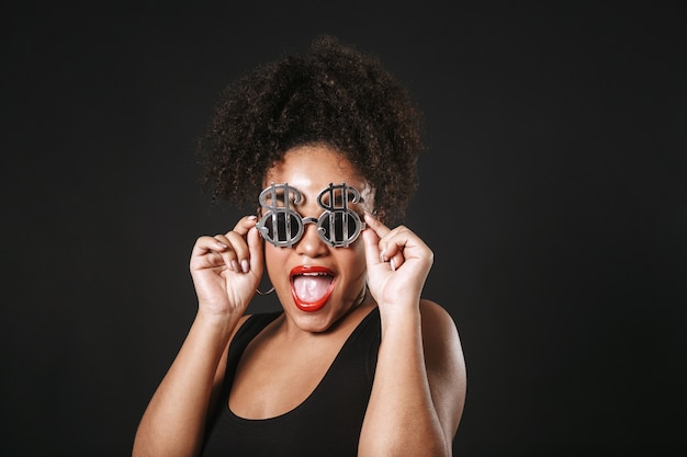 Portrait d'une belle femme afro-américaine portant des lunettes de soleil debout isolé sur un espace noir