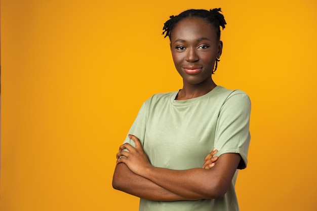 Photo portrait d'une belle femme afro-américaine positive en studio jaune