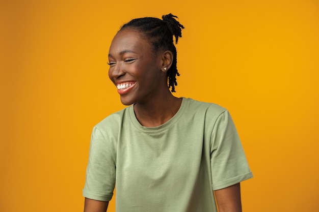 Portrait d'une belle femme afro-américaine positive en studio jaune