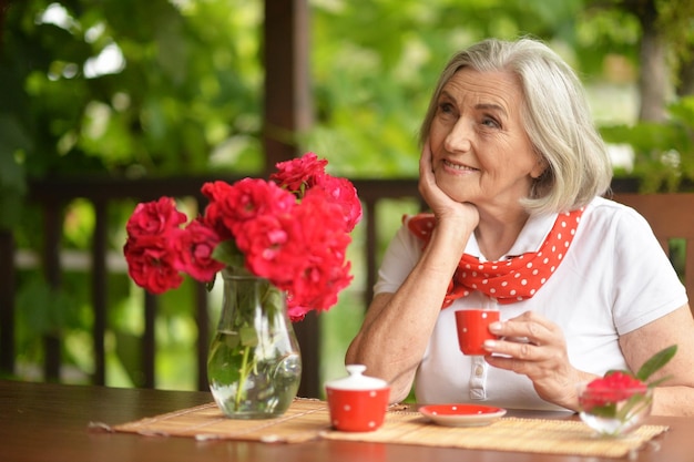 Portrait d'une belle femme âgée heureuse buvant du café et posant